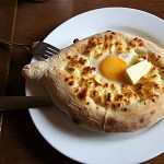 Khachapuri, filled with cheese and topped with a soft-boiled egg and butter.